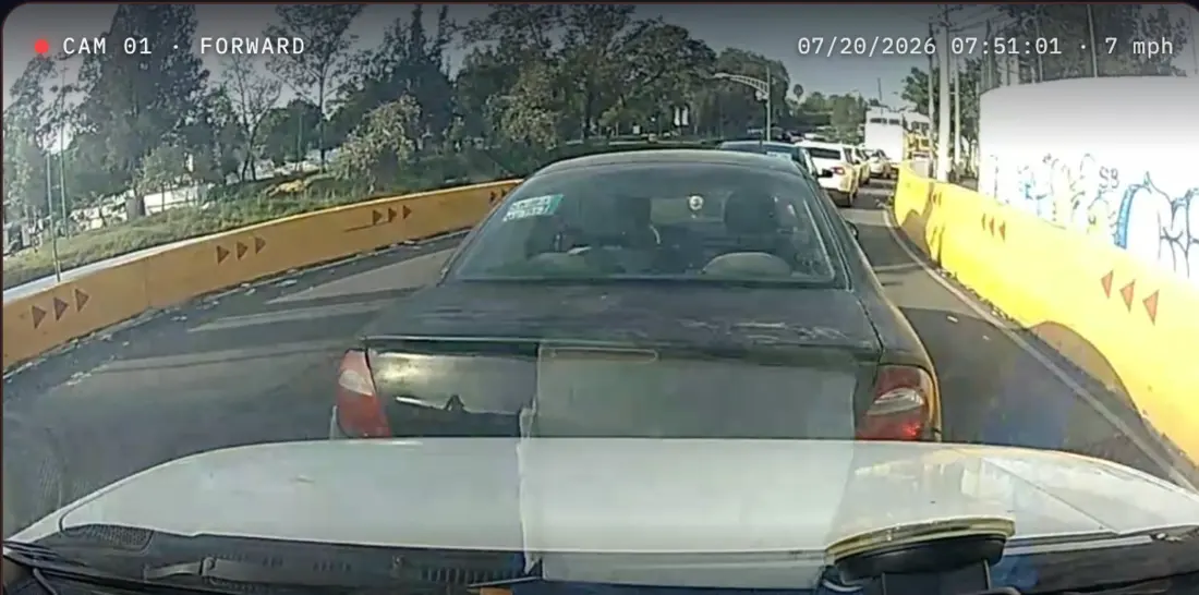 Forward dashcam still in stop-start congestion, a car cutting in close ahead between barriers, with the camera's own overlay reading CAM 01 · FORWARD and 07/20/2026 07:51:01 · 7 mph.